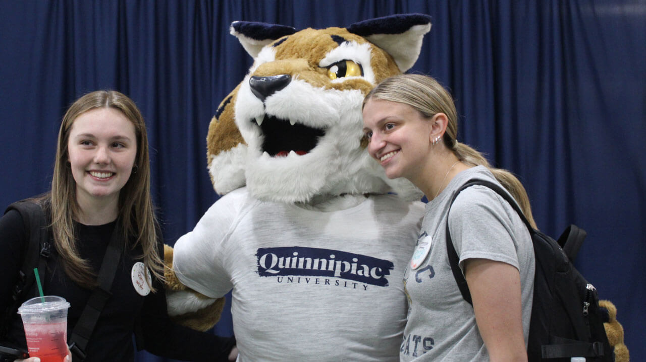 Boomer stands with two students