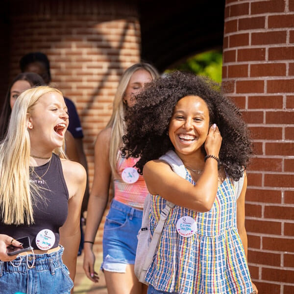 Two students walk and laugh together during Orientation