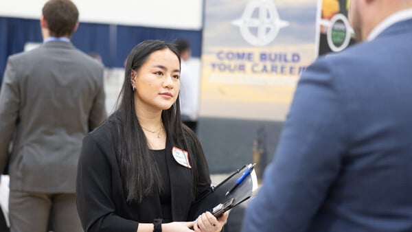 A female student holding a folder looking at someone off camera