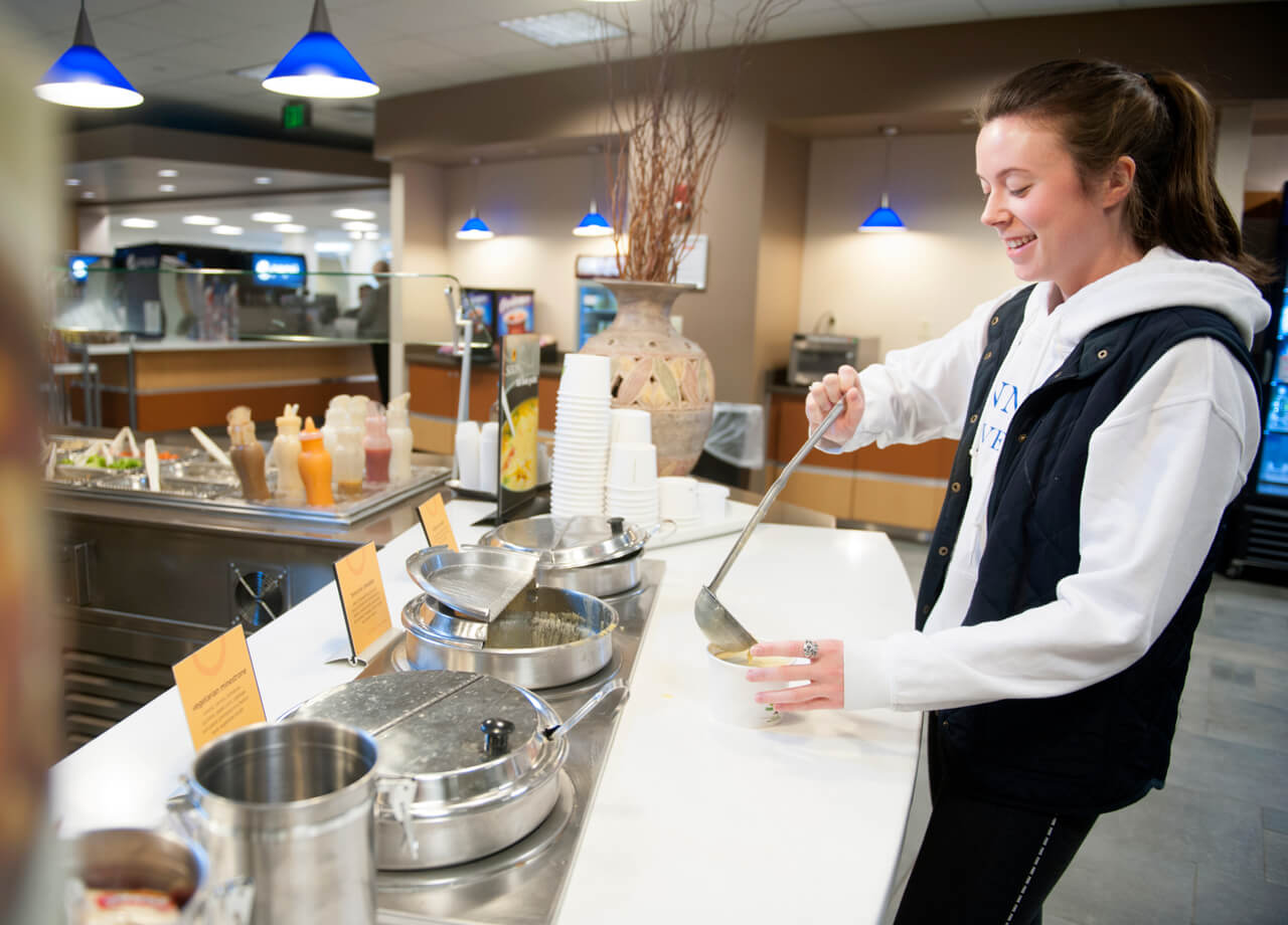A student pours soup into a cup in the North Haven Campus dining hall