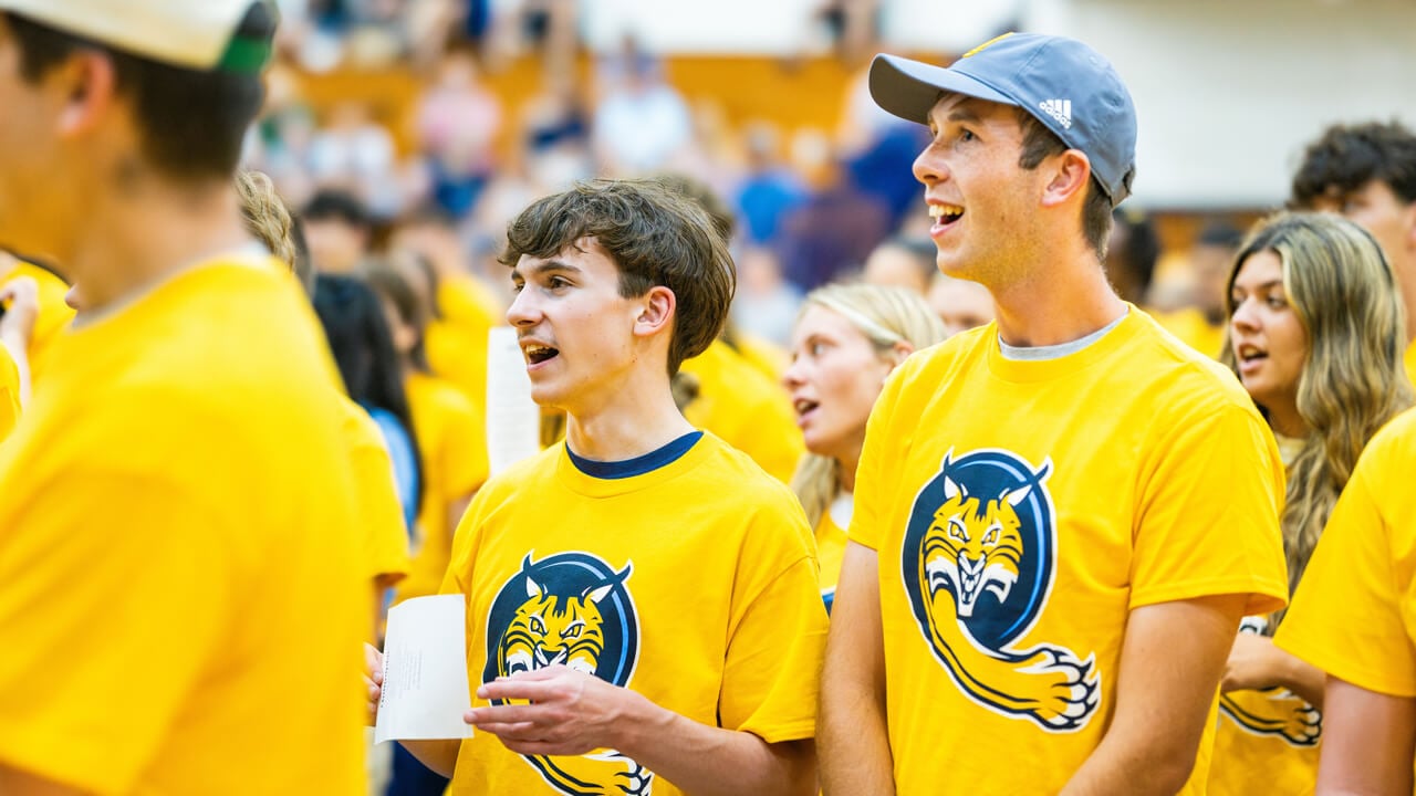 Students sit in the crowd wearing yellow shirts