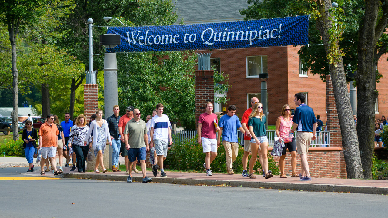 A group of people walk around campus with a student tour guide