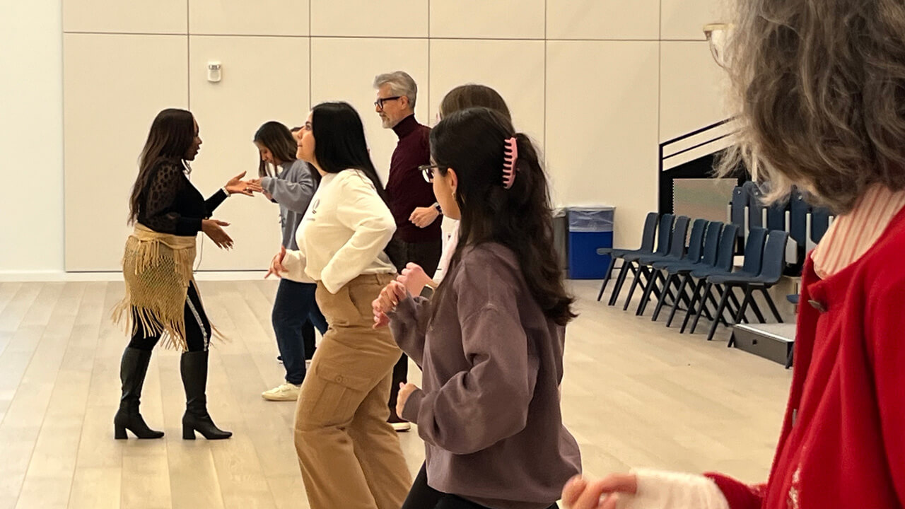 A line of students and faculty members practicing partner dancing in the SITE auditorium with instructor Alisa Bowen.