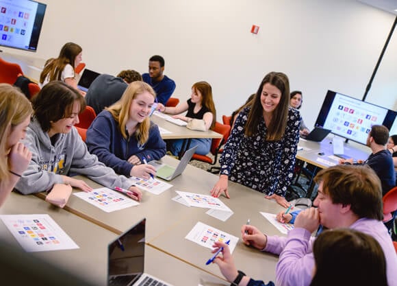 Students discuss and observe various advertising campaigns with a professor in the School of Communications