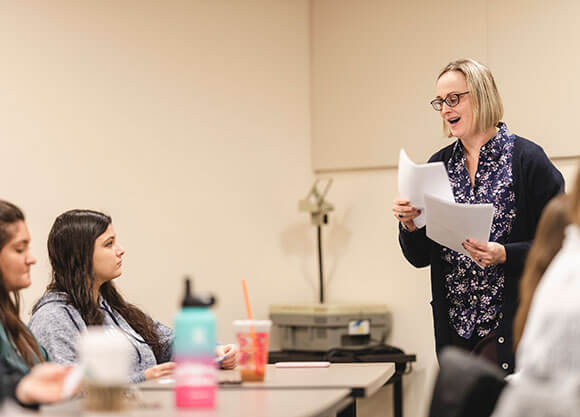 Professor Jill Fehleison talk to her students and hands out papers