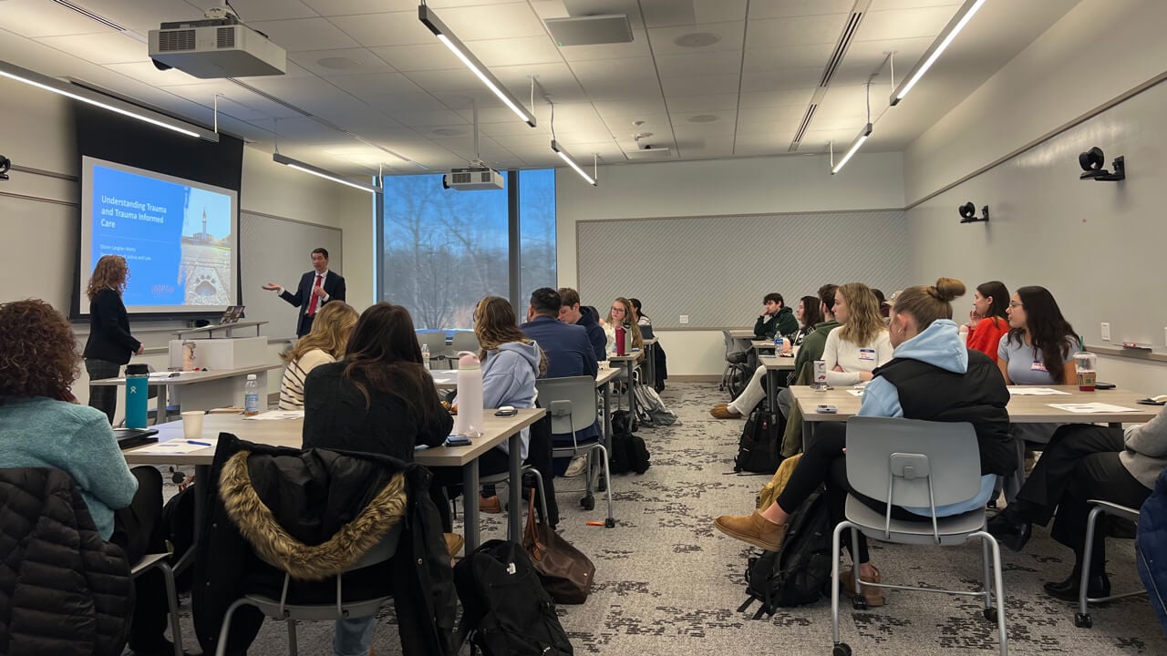 A wide shot of the classroom with Professor Langlan-Wortz and Marc Pelka in front.