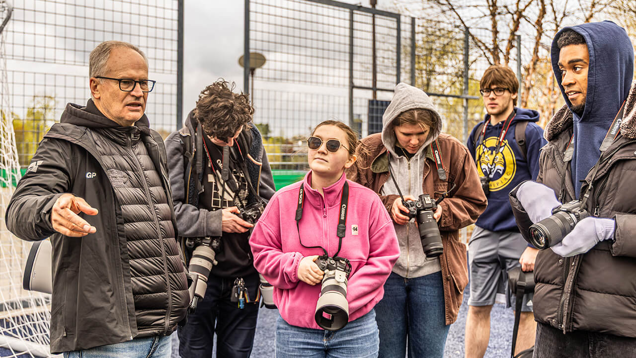 A group of student with cameras looking at Simon Bruty as he speaks