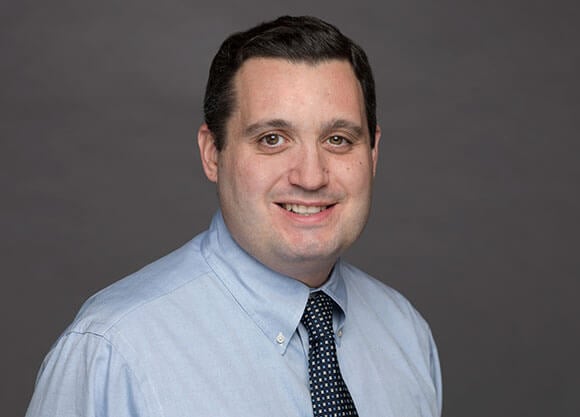 Headshot of Ben Bogardus smiling while wearing a button up and navy blue tie