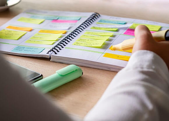 Person highlighting their calendar with sticky displayed all over it