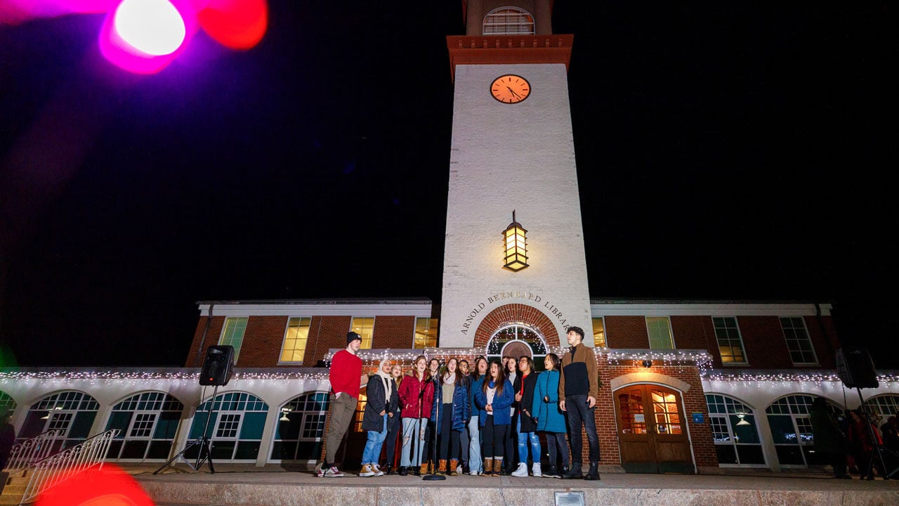 Holiday lights on Arnold Bernhard Library and students walking around