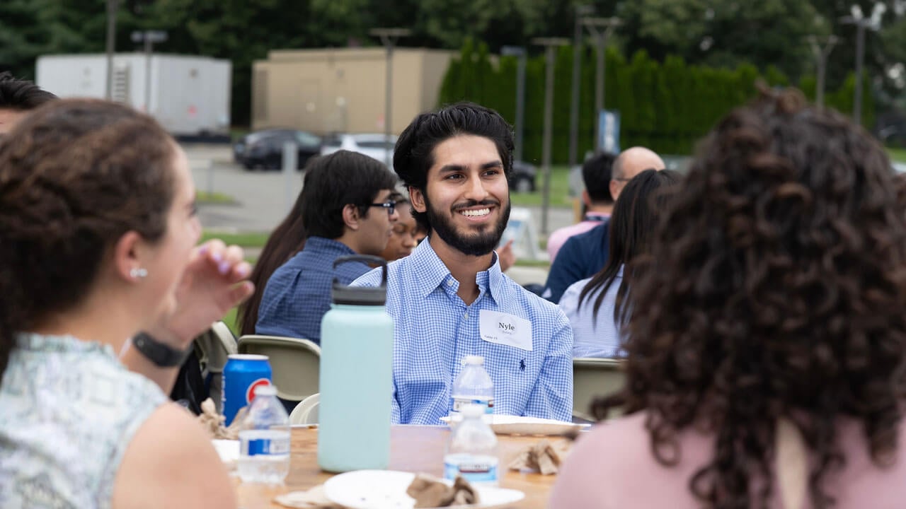 Student sitting at table with other students smiling