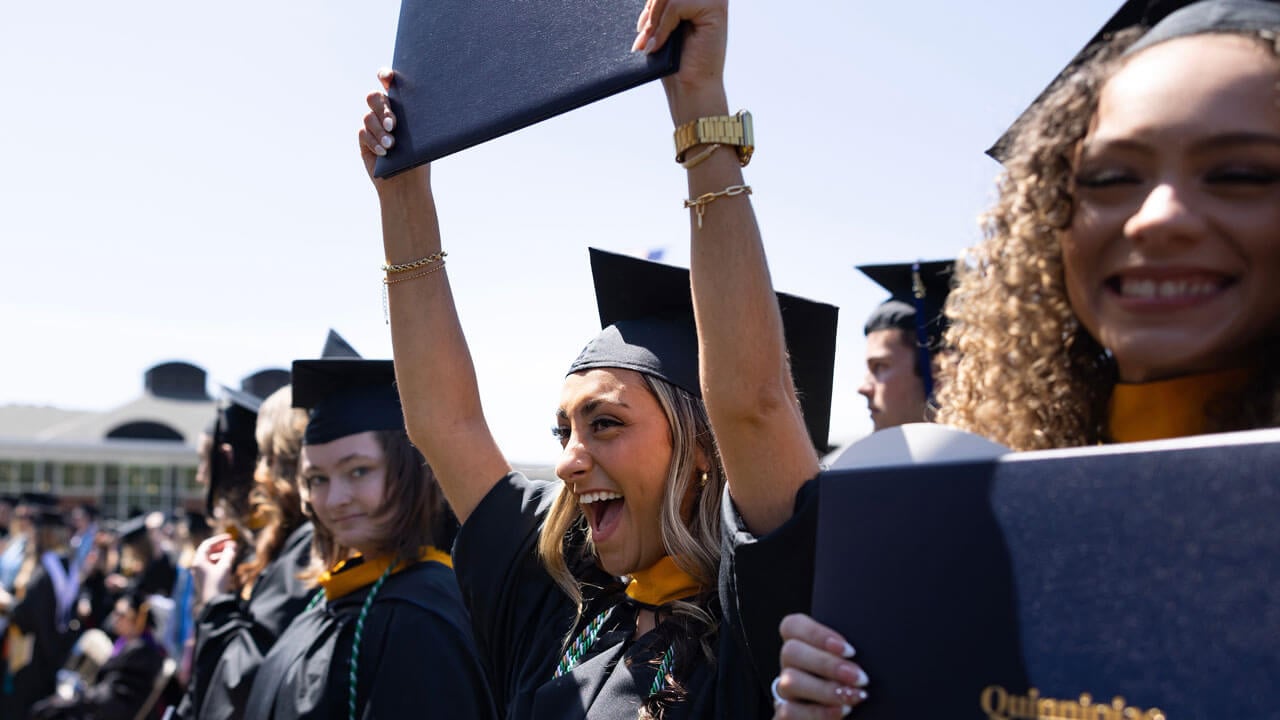 Girls holding up their diplomas eagerly and cheering