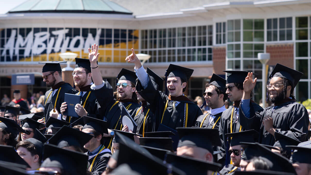 Group of friends cheering dressed in graduation robes