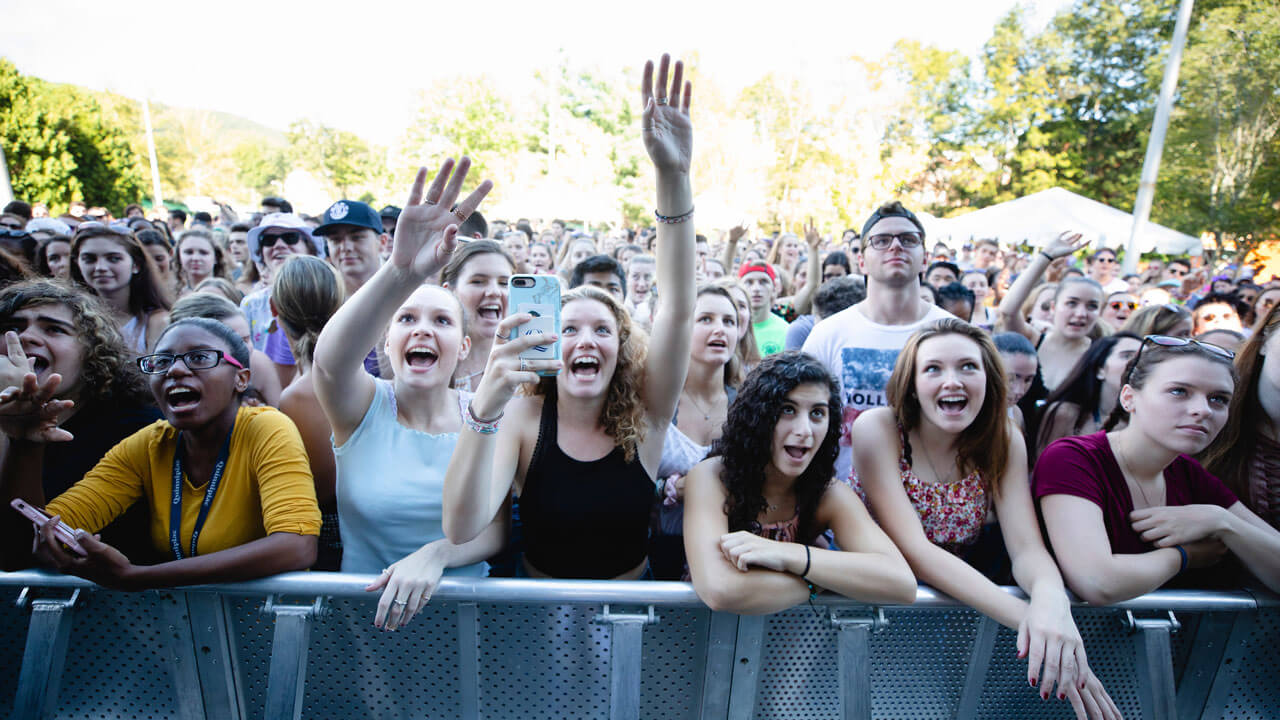 Students pressing against barrier with phones recording show