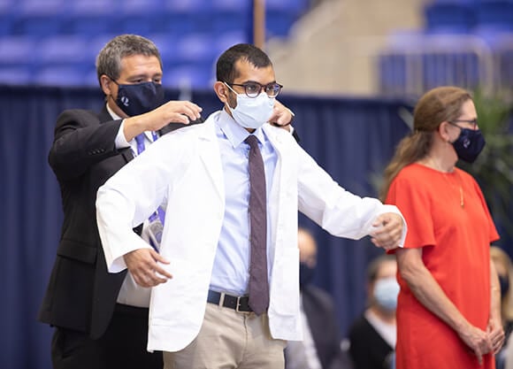 A student receives his white coat.