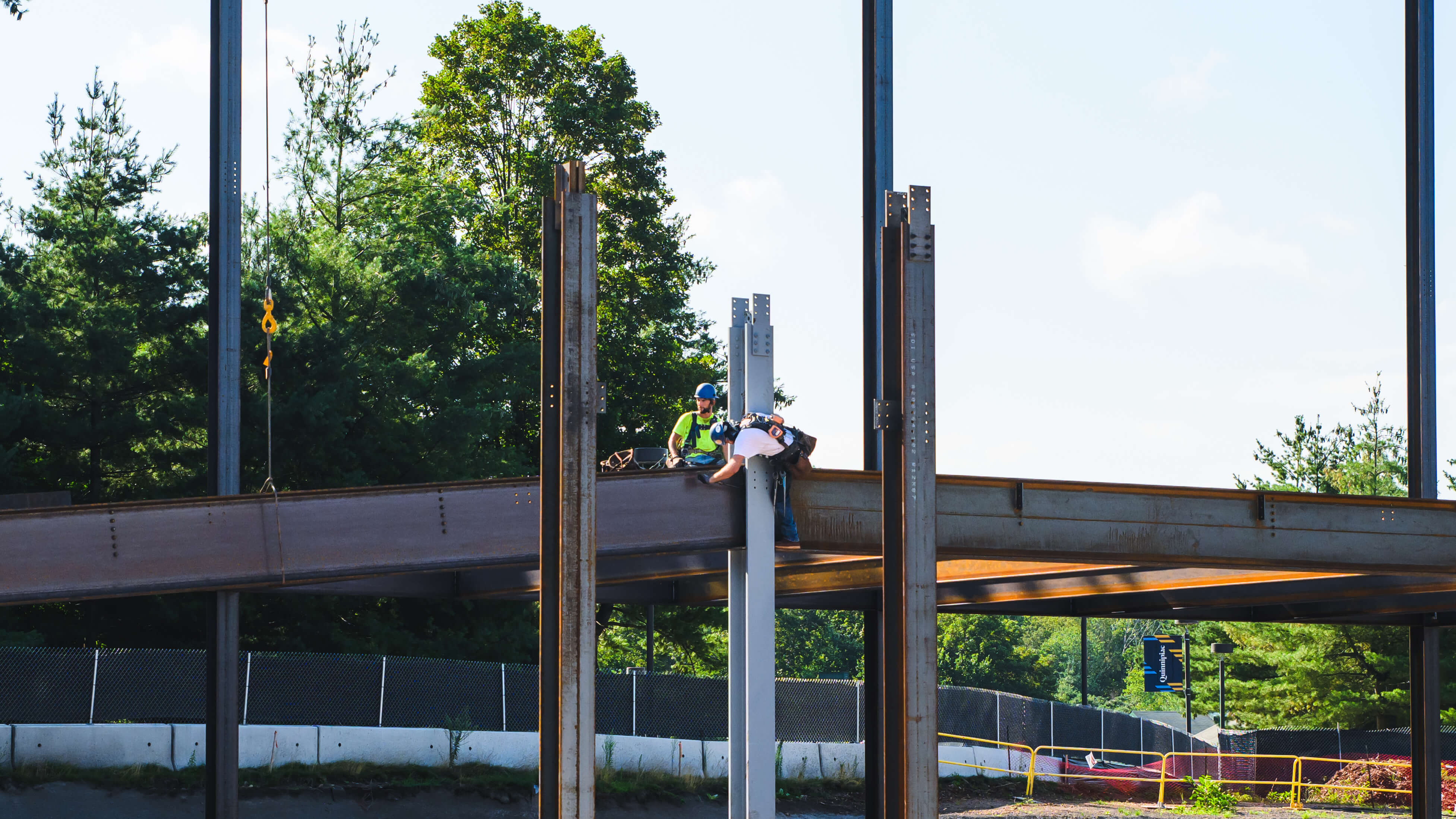 Workers screw in bolts atop a beam