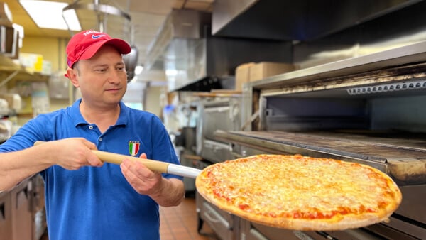 Gino of Tonino's pizza removes a cheese pie from the oven