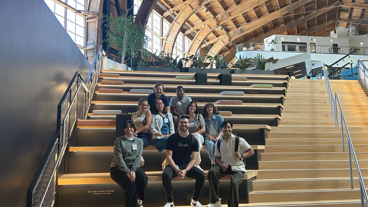 Sam Bloch sitting in the middle of current Quinnipiac students within the Google campus