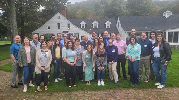 Faculty and staff alumni pose for a picture at Alumni Gardens on the Mount Carmel campus.