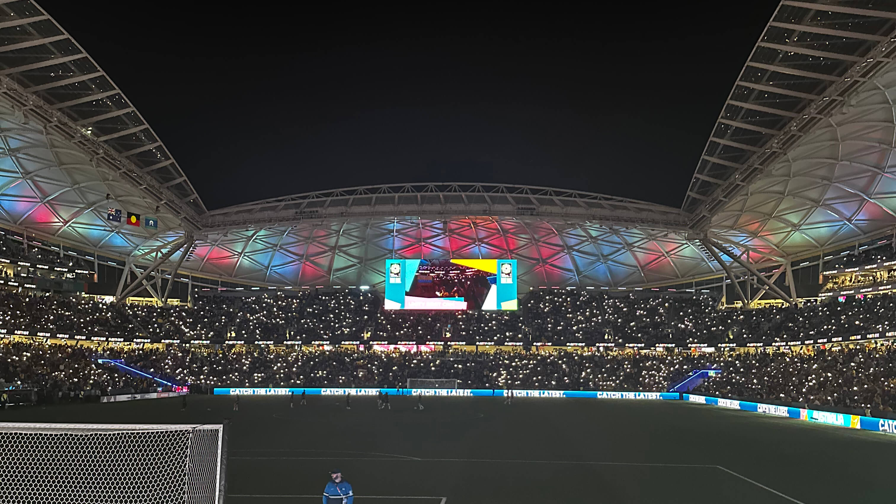 Soccer field inside stadium with fans holding flashlights up in the crowd