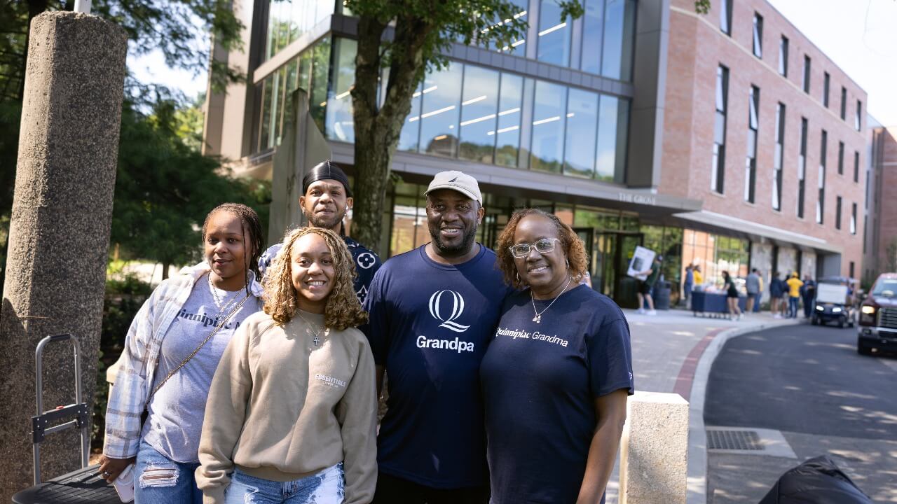 Student and family standing outside The Grove residence hall on move-in day