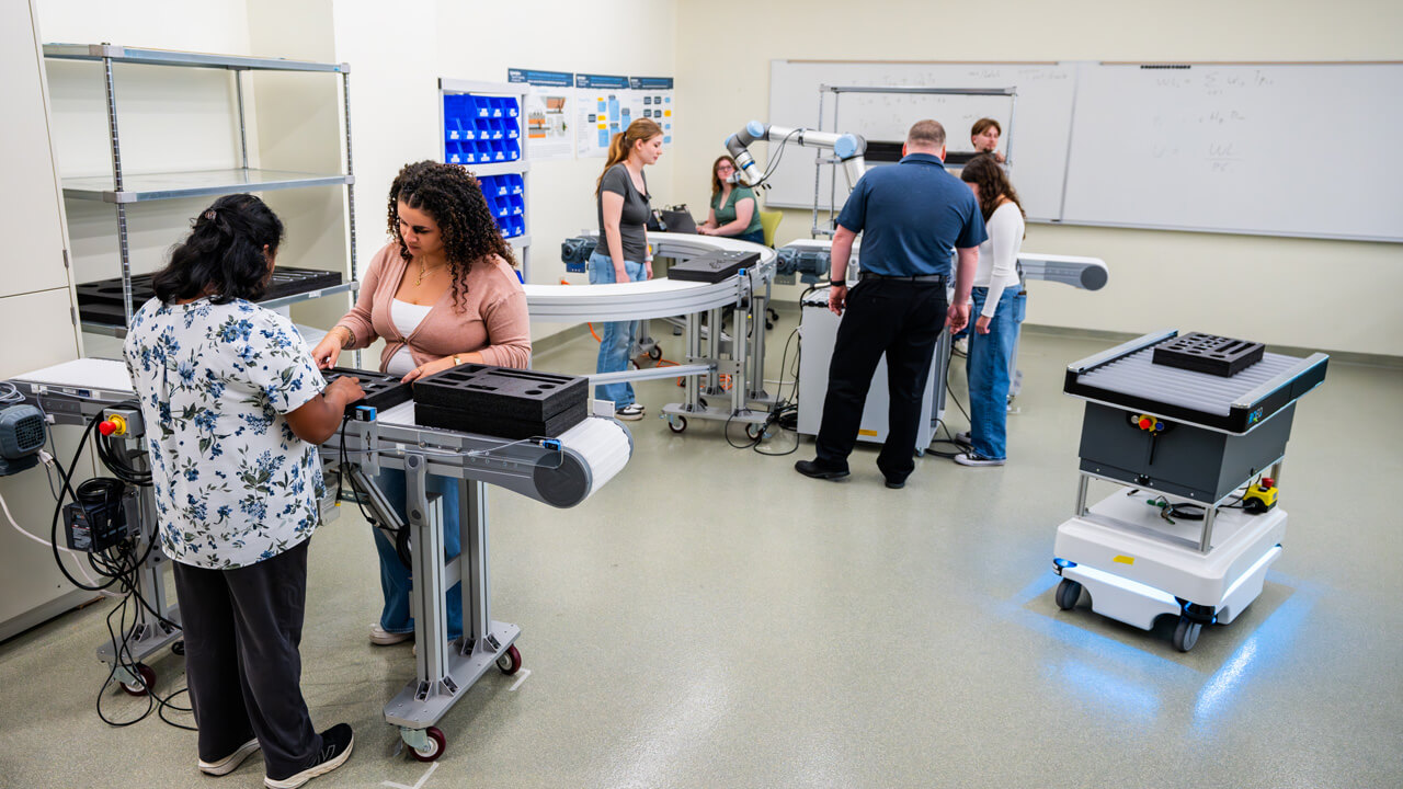 Two groups of faculty and students use machinery in the Industrial Engineering Room.