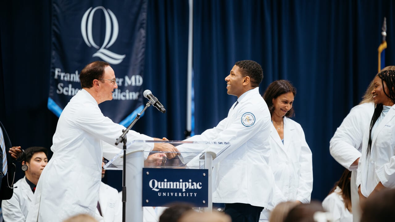 Two individuals shake hands on stage