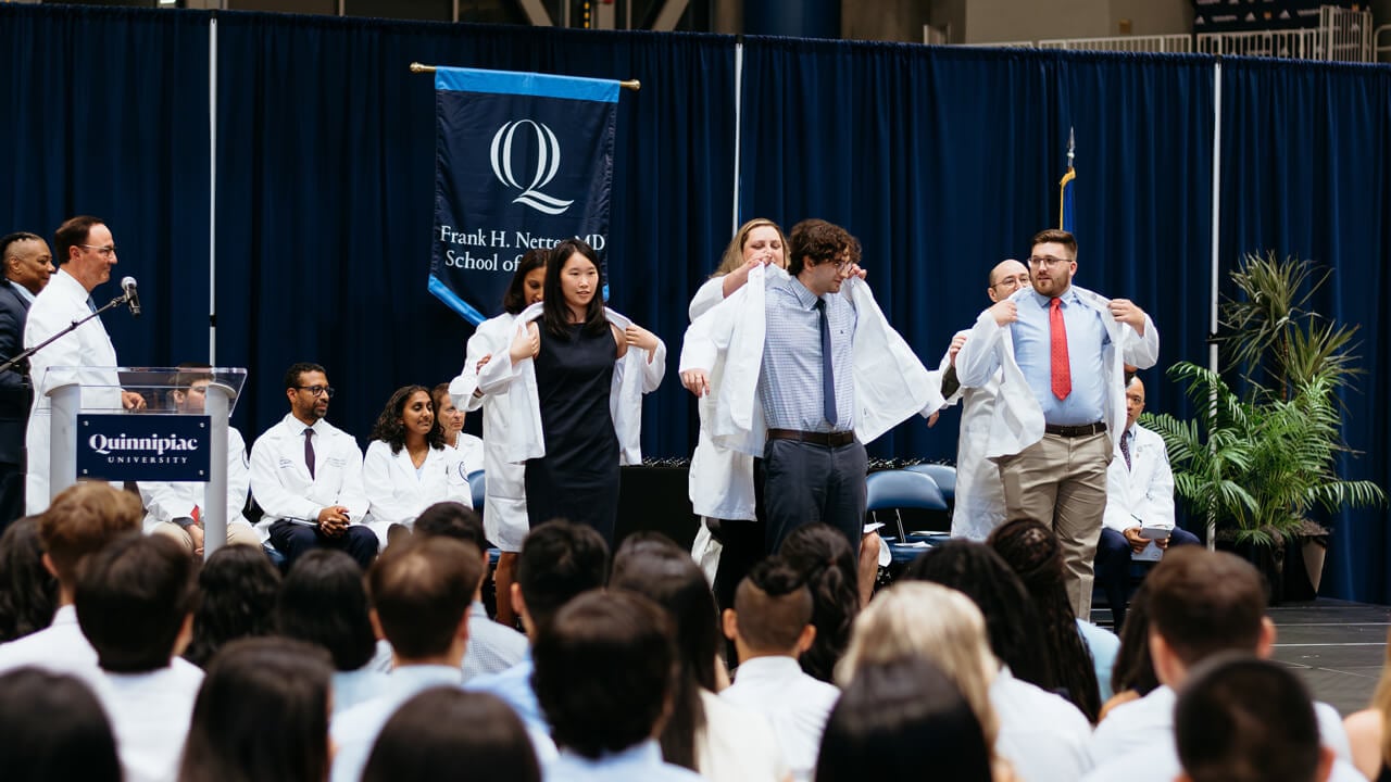 Students receive their white coat on stage