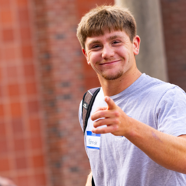 A new student smiles and points at the camera as he moves in at Quinnipiac