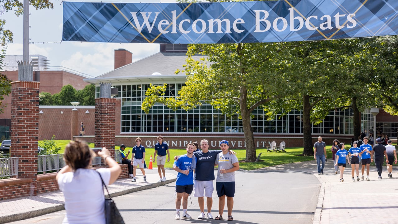 A student poses for a photo with loved ones under a Welcome Bobcats sign