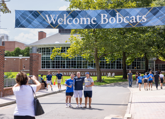 A student poses for a photo with loved ones under a Welcome Bobcats sign