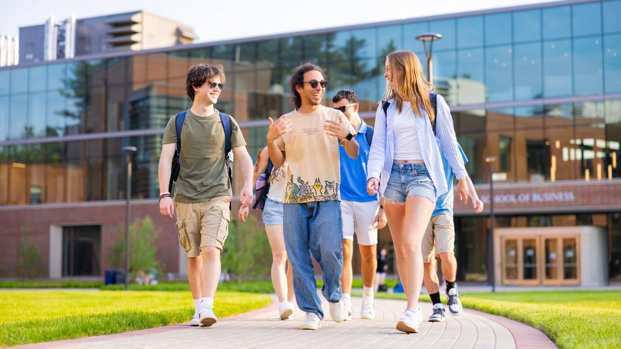 Six students walk and talk together across the South Quad on a sunny day