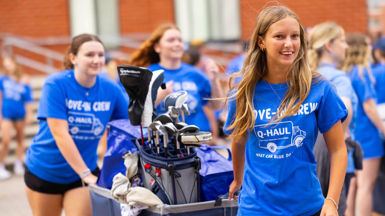 Students carry boxes and bags, helping first year students move into their dorms.