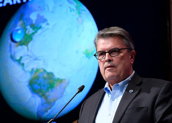 Craig McClean with an image of the world behind him speaking at the Aspen Ideas Festival