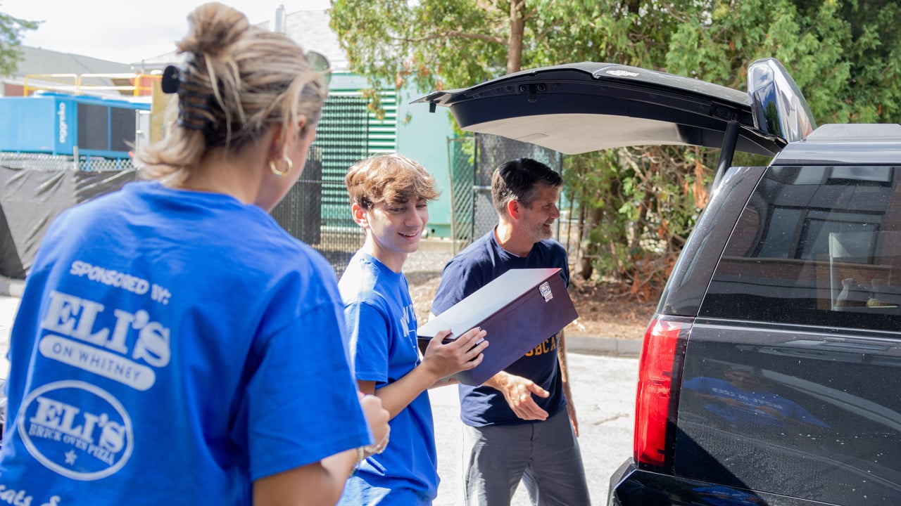 Students lifting boxes from a car trunk