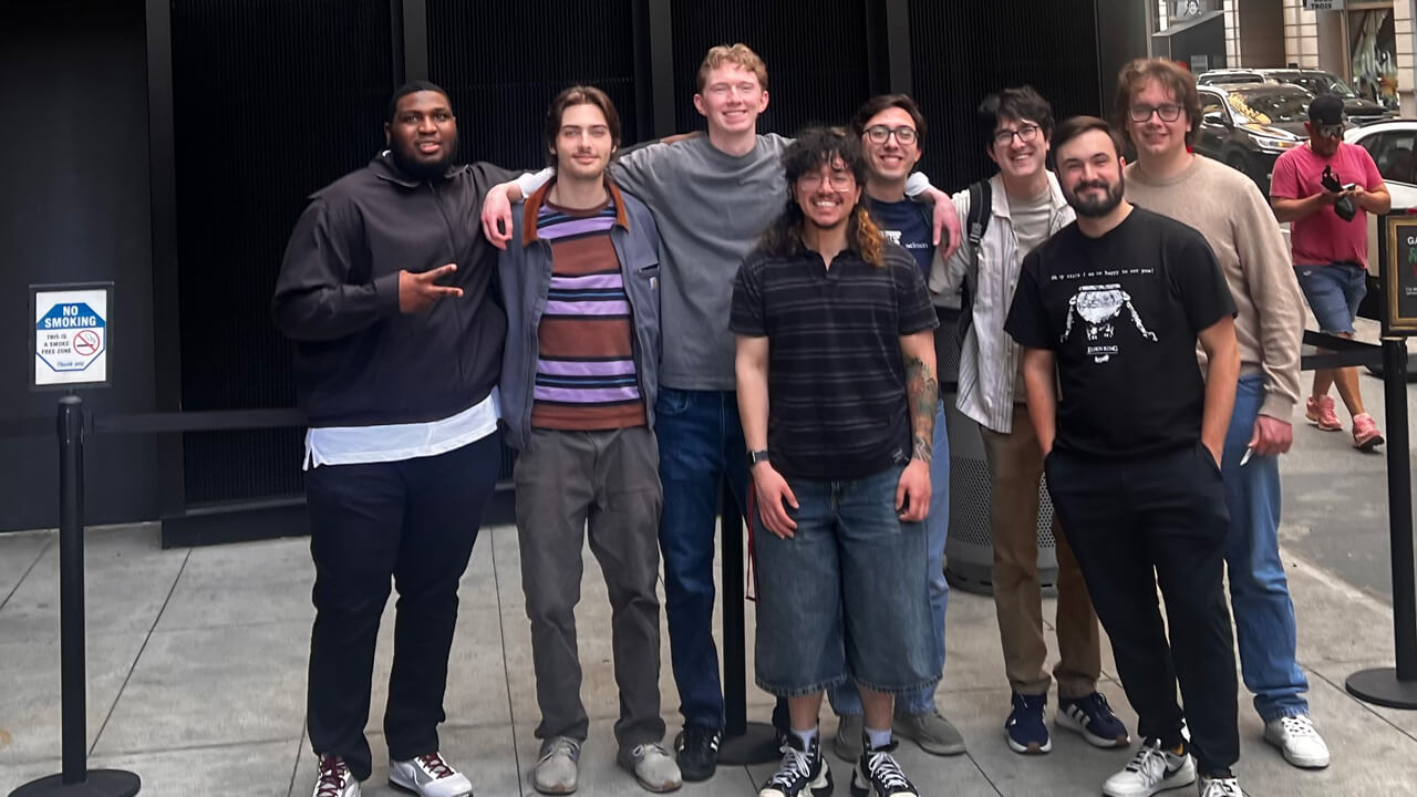 Eight students standing on a city street outside of the T2 building.