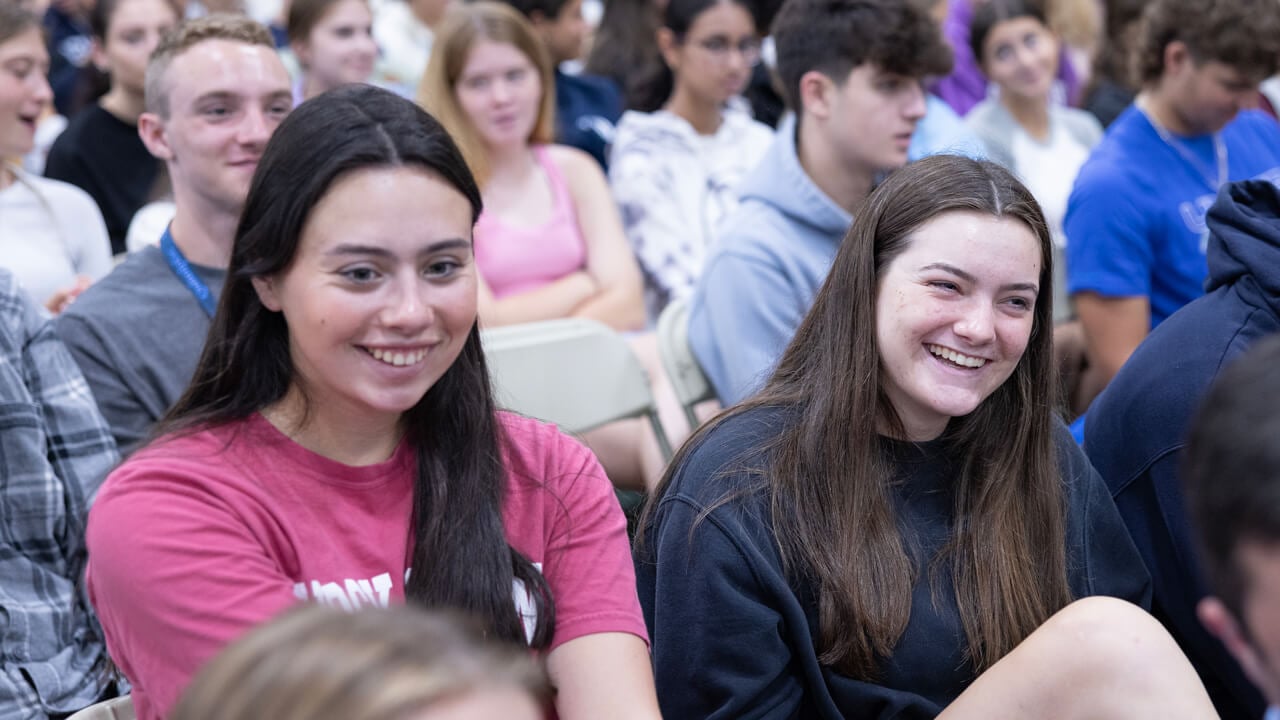 Several students sit in chairs as they listen to speakers during the welcome ceremony