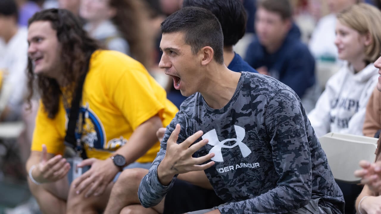 Two students cheer as they do a Quinnipiac Bobcat swipe with their arm