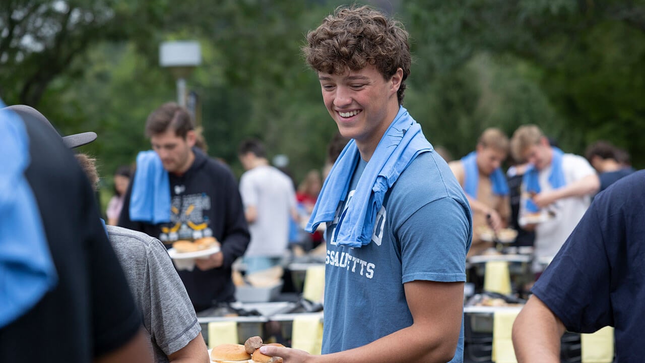 Boy in blue t-shirt smiling while looking down at food