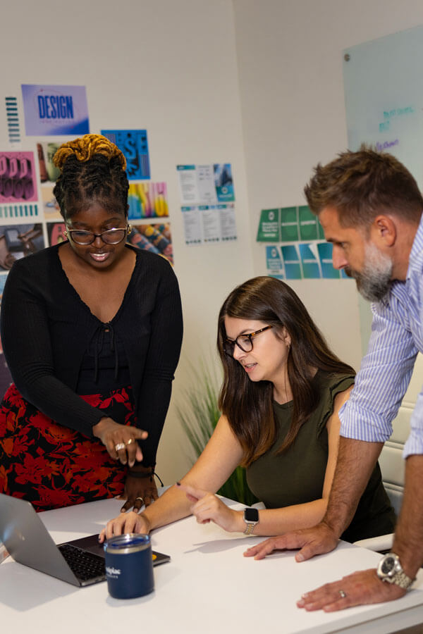 Graduate students and professionals collaborate on a laptop in an office