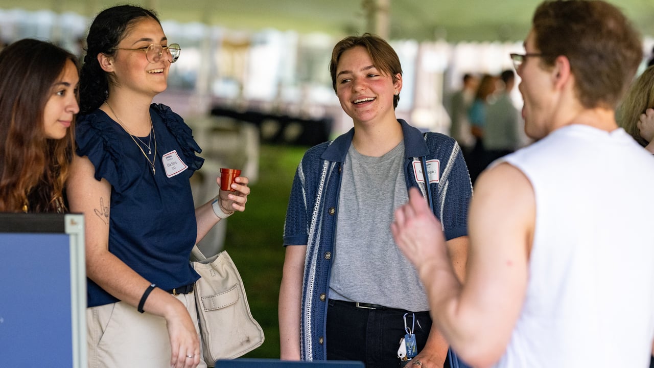 Students talk while holding a plant