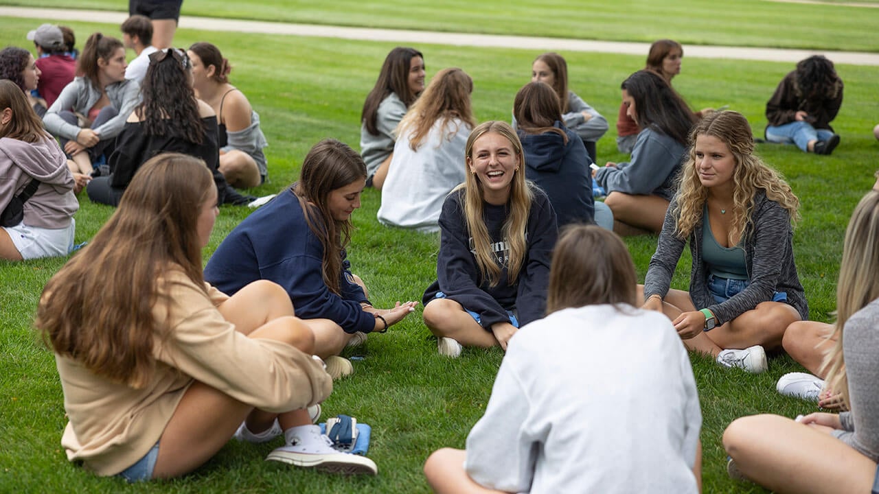 Girls sitting in a circle laughing on grass