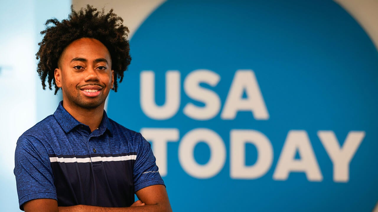 Toyloy Brown smiles in front of a USA Today sign