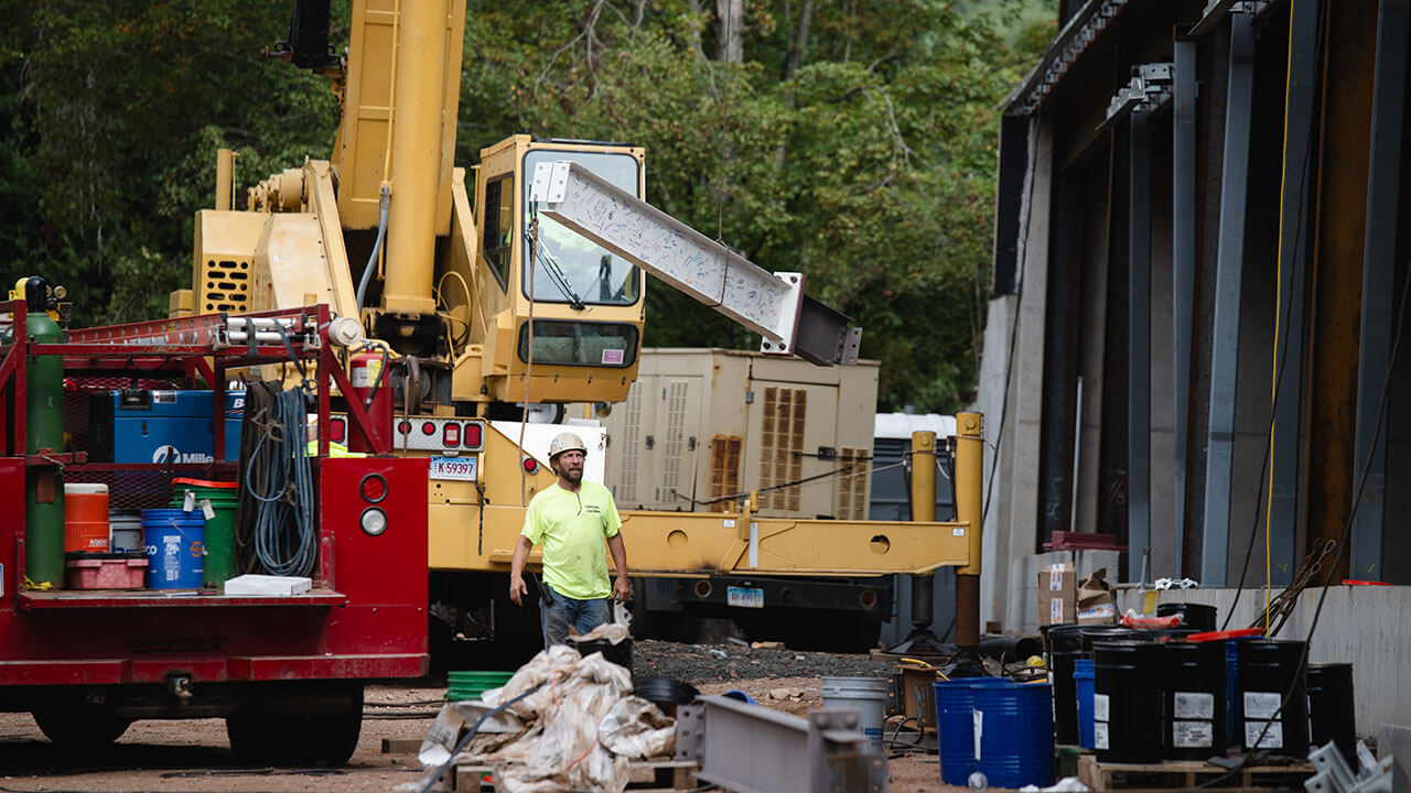 Construction worker in neon green shirt looks up at beams