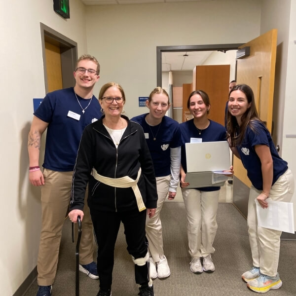 A photo of a female EQUIP patient with a cane and four students.
