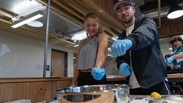 Two students pouring ingredients into a bowl during a cooking class offered at the RecWell Center