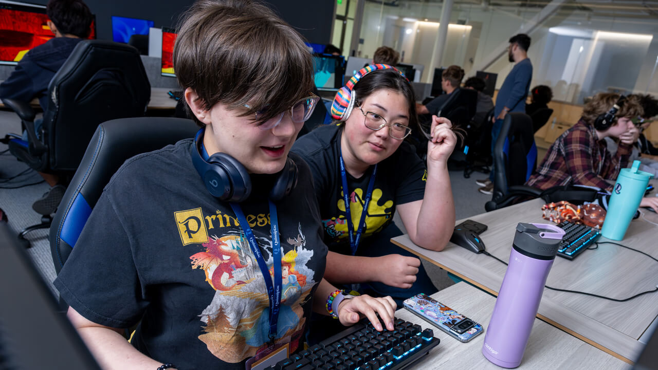 Two students sitting together close to a keyboard.