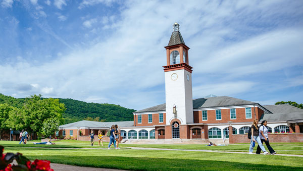 Students walking across the quad in front of the Arnold Bernhard Library