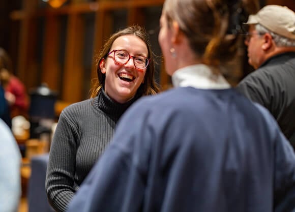 Two women, one in a judge's robe, smiling and having a conversation.