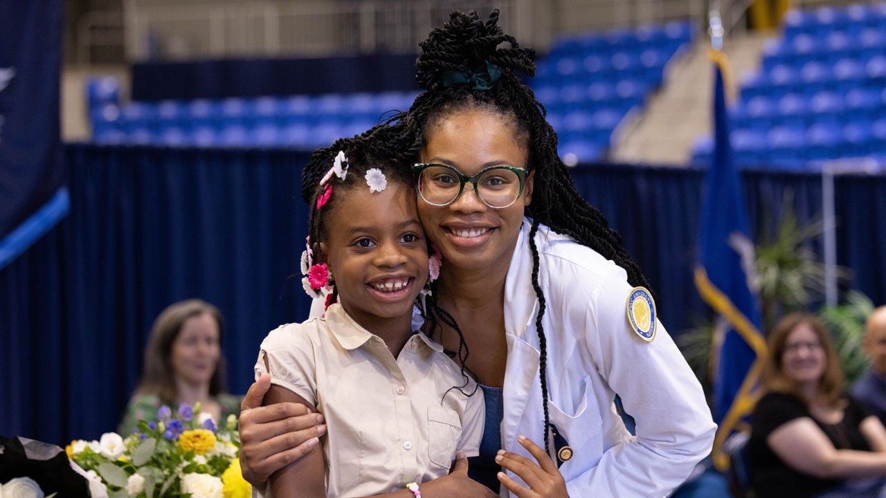 Nursing student embraces family member and smiles for a photo